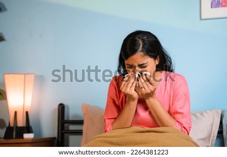 Young girl suffering from cold by sneezing at home whille sleeping on bed - concept of healthcare, infection and unhealthy. Royalty-Free Stock Photo #2264381223