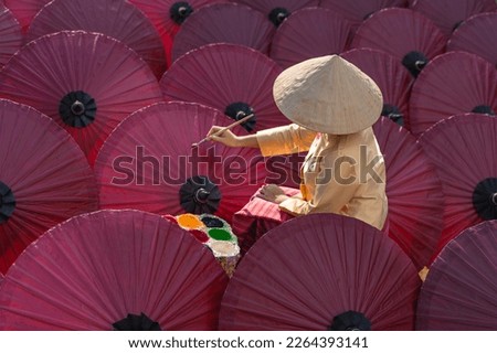 Women paint beautiful paper umbrella Traditional handmade umbrella a product that is unique and popular as a souvenir for tourists in travel of Chiang Mai, Northern Thailand. Background concept. Royalty-Free Stock Photo #2264393141