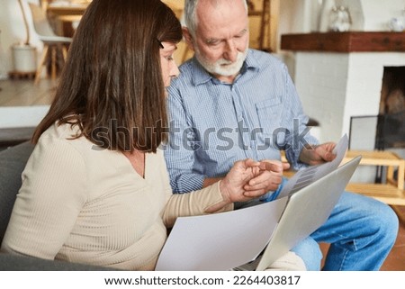 Two seniors sort through finances and insurance together on the computer at home and on the Internet