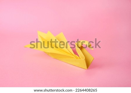 Origami art. Beautiful paper swan on pink background