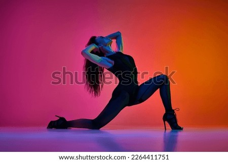 Flexibility and passion. Young woman dancing high heel, contemp dance over gradient pink red studio background in neon light. Contemporary dance style, art, aesthetics, hobby, creative lifestyle Royalty-Free Stock Photo #2264411751