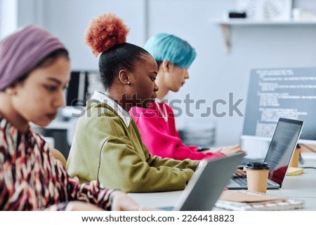 Diverse group of creative young people sitting in row while working in office focus on black young woman using laptop Royalty-Free Stock Photo #2264418823