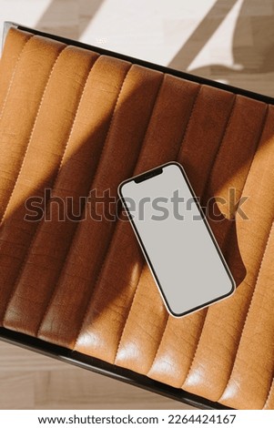 Flatlay mobile phone on orange leather bench with sunlight shadows. Aesthetic elegant blog, online shopping, online store, social media branding template with blank copy space
