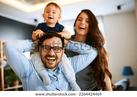 Young father holding the son in his arms while the mother watches them in their home Royalty-Free Stock Photo #2264424469