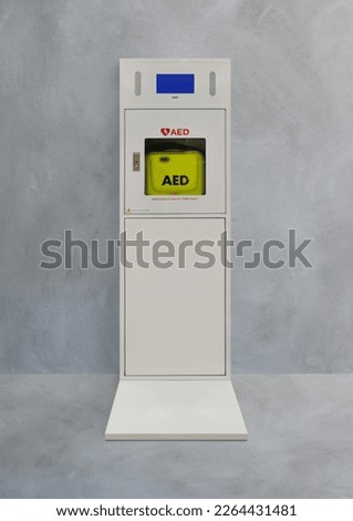 Automatic electric defibrillator isolated on cement background