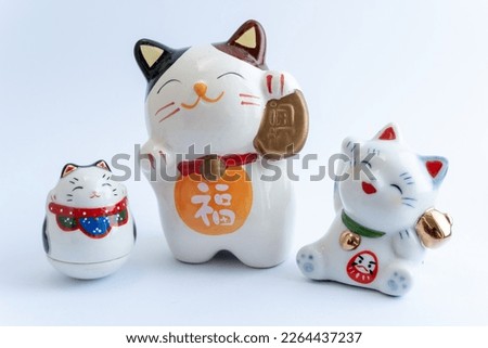 A Maneki-neko or also known as fortune cat in porcelain. Symbolizing luck and wealth, on a white isolated background. Chinese character translate as "blessing".