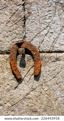 Old rusty horseshoe hanging on the stone wall of farmhouse. 