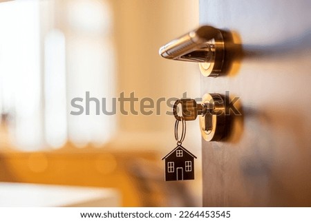 Open door to a new home. Door handle with key and home shaped keychain. Mortgage, investment, real estate, property and new home concept Royalty-Free Stock Photo #2264453545