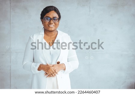 Smiling African American business woman wearing stylish eyeglasses looking at camera standing in modern office. Successful business and career concept. Young business woman in modern office 