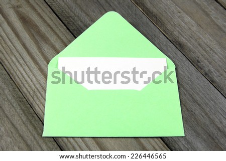 green open enveloped with blank card on wooden background