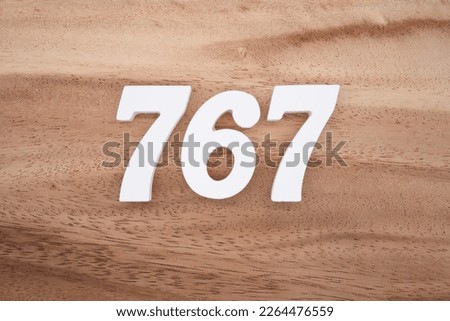 White number 767 on a brown and light brown wooden background.