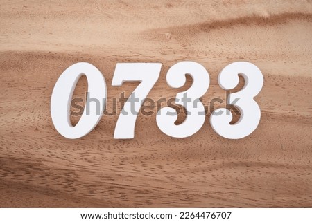 White number 0733 on a brown and light brown wooden background.