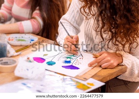Painting Workshop. Women paints picture on canvas with watercolor paints in her studio
