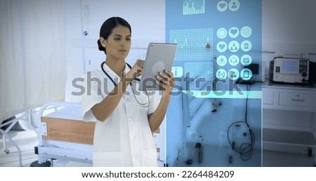 Composition of biracial female doctor using tablet over digital interface and room in hospital. Medicine, healthcare and digital interface concept digitally generated image.
