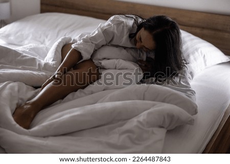 A young woman got severe cramps in her calf at night while sleeping. Royalty-Free Stock Photo #2264487843
