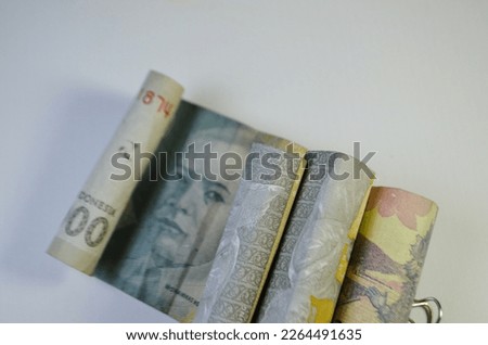 Rupiah rolls are arranged in such a way on a white background to form a unique shadow