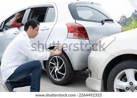 Asian men driver check for damage after a car accident before taking pictures and sending insurance. Online car accident insurance claim after submitting photos and evidence to an insurance company.