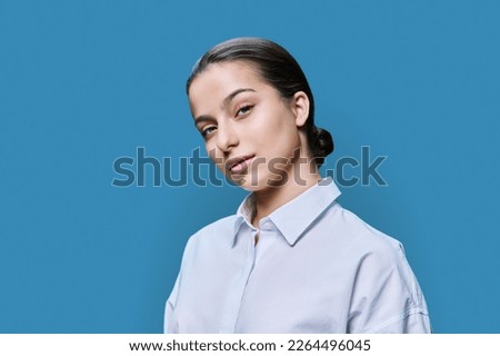 Portrait of young pretty teenage female posing against blue studio background