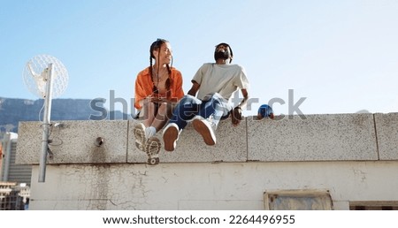 Love, friendship and a couple sitting on rooftop of city building in summer time. Diversity, friends and romance, gen z urban dating for happy woman and black man with smile and skateboard on date. Royalty-Free Stock Photo #2264496955