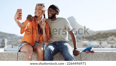 Happy, skateboard and couple taking a selfie on a phone while sitting on a rooftop in the city. Happiness, peace sign and young interracial man and woman taking photo with smartphone in a urban town.