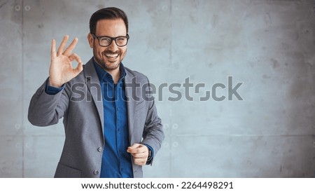 Portrait of happy young business man showing an OK sign isolated. Portrait of happy business man wearing spectacles and looking at camera with copy space. Satisfied proud man feeling confident  Royalty-Free Stock Photo #2264498291