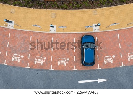 Aerial view directly above an electric vehicle charging station with parking spaces and road markings denoting charging bays