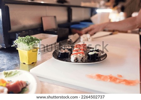 Watch a skilled sushi chef prepare and serve an array of fresh sushi rolls in this visually stunning image