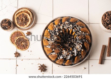 Vanilla bundt cake with chocolate glaze and nuts on top, top view