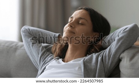 Close up satisfied attractive woman resting on couch alone, leaning back with hands behind head, stretching on cozy sofa at home, enjoying lazy weekend, stress relief and refreshment concept Royalty-Free Stock Photo #2264507985
