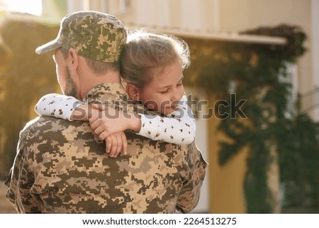 Soldier in Ukrainian military uniform hugging his daughter outdoors, space for text. Family reunion