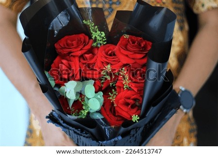 man in batik shirt bouqet of red rose flowers in hands 