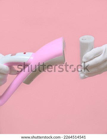 Man holding a disassembled clothes steamer with a plastic water container. pink background.