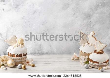 Set of traditional easter cakes with icing, decorated with gingerbread cookies in shape of rabbits and birds over white wooden background. Side view, copy space. Easter treat, holiday symbol Royalty-Free Stock Photo #2264518535