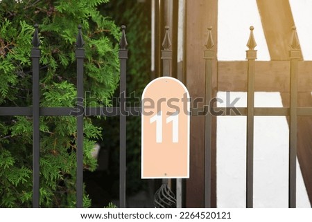 Plate with house number eleven hanging on iron fence outdoors