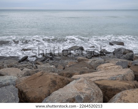 resort in winter. The rocky shore is washed by the waves in cloudy weather. Black Sea coast. The coast of Batumi. Nature in shades of grey. Grey. boring landscape