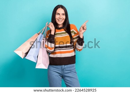 Photo of sweet cute lady dressed striped pullover showing looking empty space holding bargains isolated teal color background