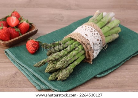 A bunch of green asparagus with fresh strawberries.