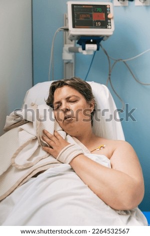 Female patient trying to sleep with a blanket while sitting in a hospital chair.