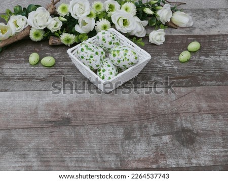 Flower decoration with green easter eggs on wooden background.