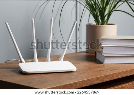 New white Wi-Fi router on wooden table indoors Royalty-Free Stock Photo #2264537869
