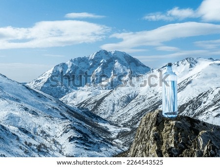 Bottle of healthy natural mineral water on a rock in an ecological landscape snowy mountain in winter in the background Royalty-Free Stock Photo #2264543525