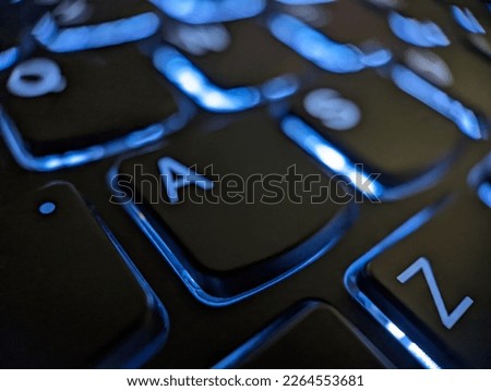 Closeup view of A and Z keys on a black laptop keyboard with glowing blue lights