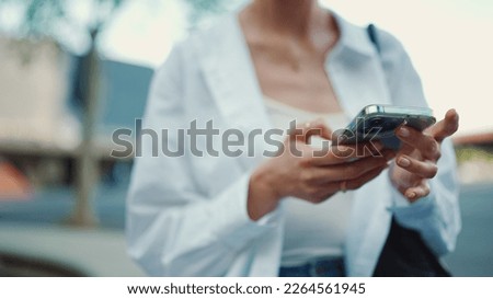 Closeup of young woman holds smartphone in her hands and scrolls through the news feed. Close-up of girl hand uses mobile phone outdoors Royalty-Free Stock Photo #2264561945