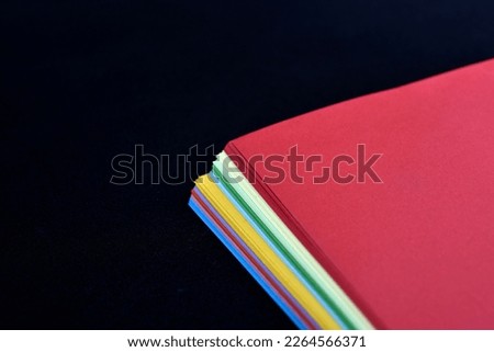 Multicolored sheets of paper on a black background. Colored office paper. A pack of colored paper.