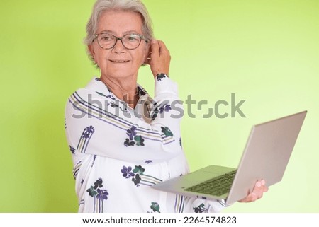 Portrait of attractive senior caucasian business woman holding laptop in hand isolated on green background