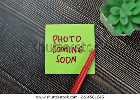 Concept of Photo Coming Soon write on sticky notes isolated on Wooden Table.