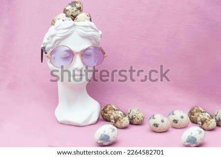 Plaster female head and quail eggs on a pink background. A postcard for Easter day with a place for the text.