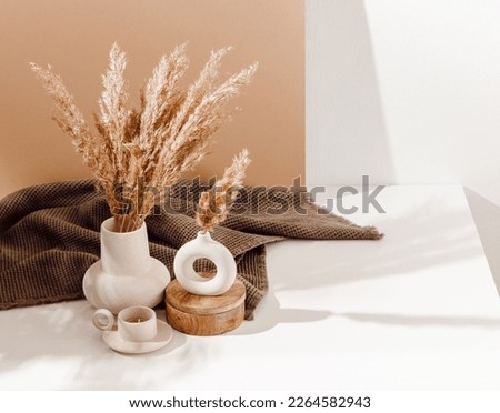Vase set with pampas grass and ceramic candle with brown towel at the background. Cozy home decorations with warm sunlight and shadows, copy space. Bohemian style