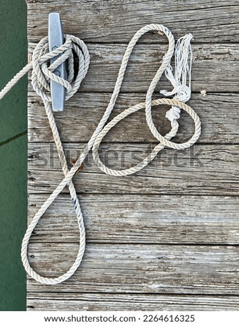 Rope for boat on Wooden Dock wrapped around Dock Cleat