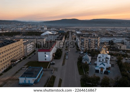Aerial view of the city at dawn. Morning cityscape. Top view of buildings, church and empty street. Hills in the distance. City of Magadan, Magadan region, Siberia, Far East of Russia. Royalty-Free Stock Photo #2264616867